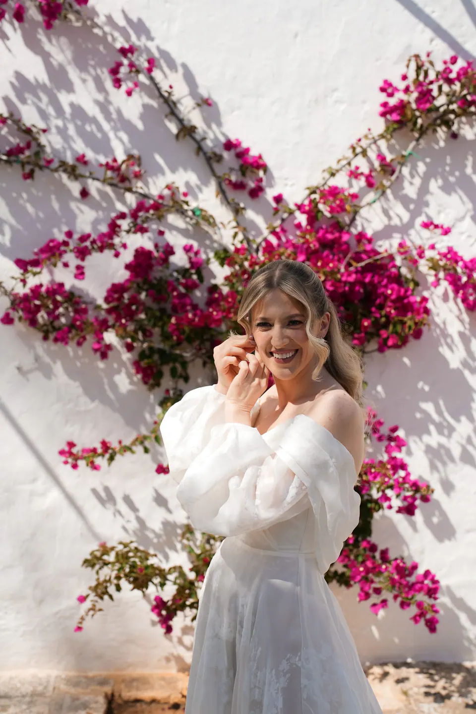 La novia ríe rodeada de flores, un momento espontáneo en Apulia.