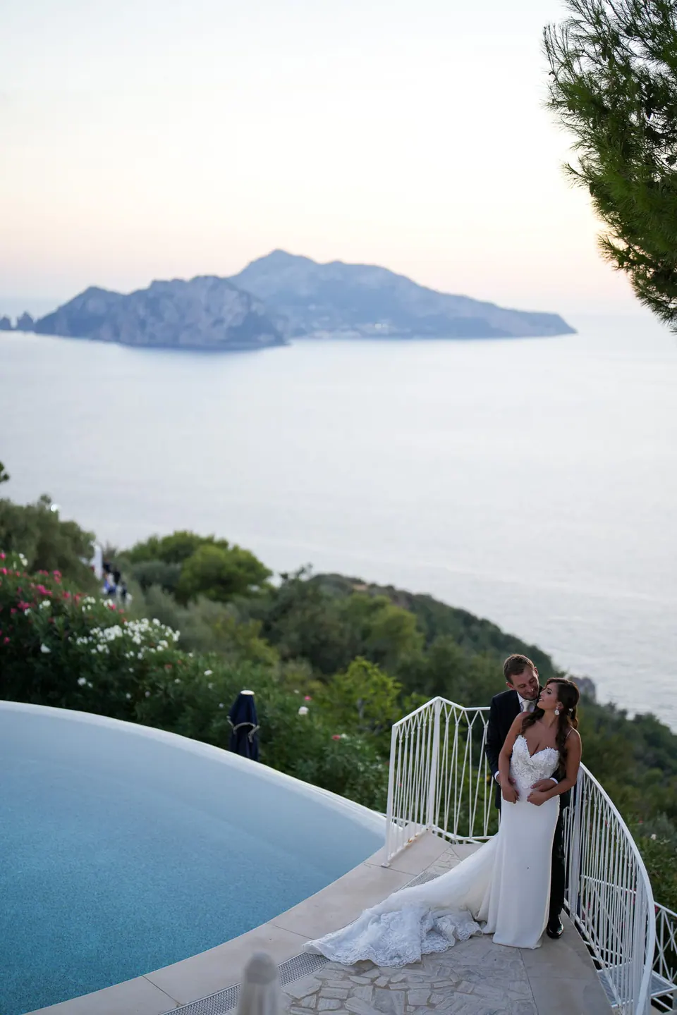 La sposa appoggiata alla ringhiera della terrazza, il mare blu che si stende all'infinito sotto di lei.