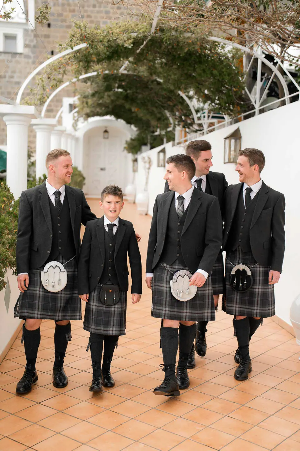 Lo sposo e i testimoni in kilt scozzese sotto la pergola bianca di Villa Milù a Praiano.
