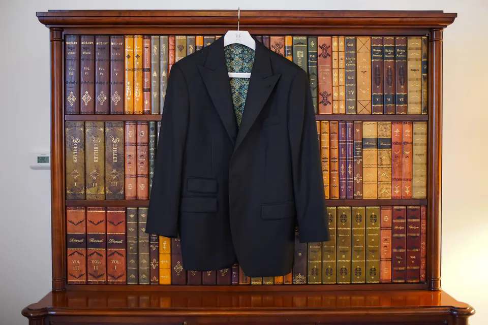 The groom's jacket hanging on a bookshelf in the suite at Belmond Hotel Caruso.