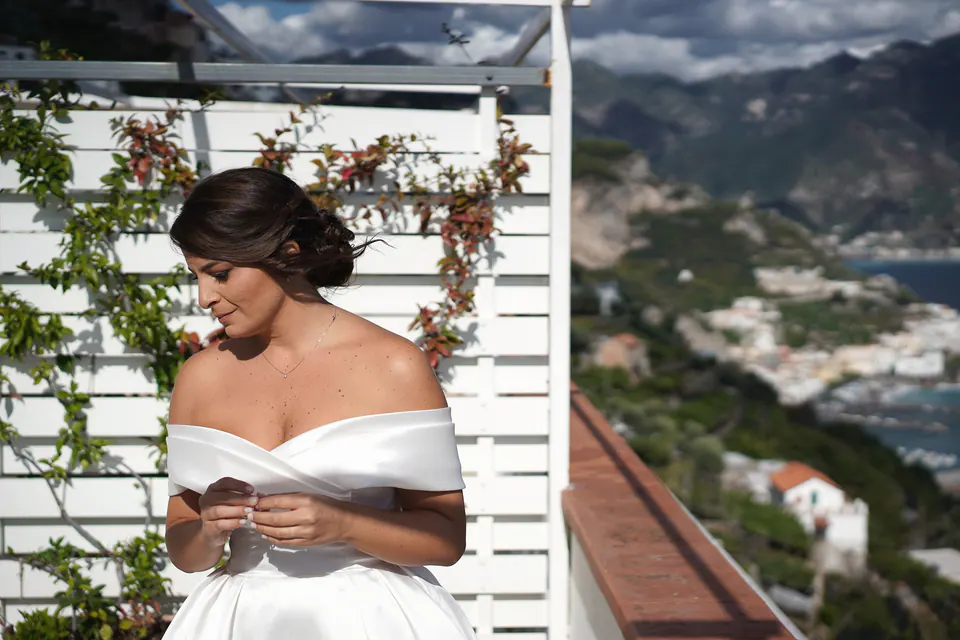 Bride on the flower-covered terrace of Le Nereidi, the Amalfi Coast behind her.