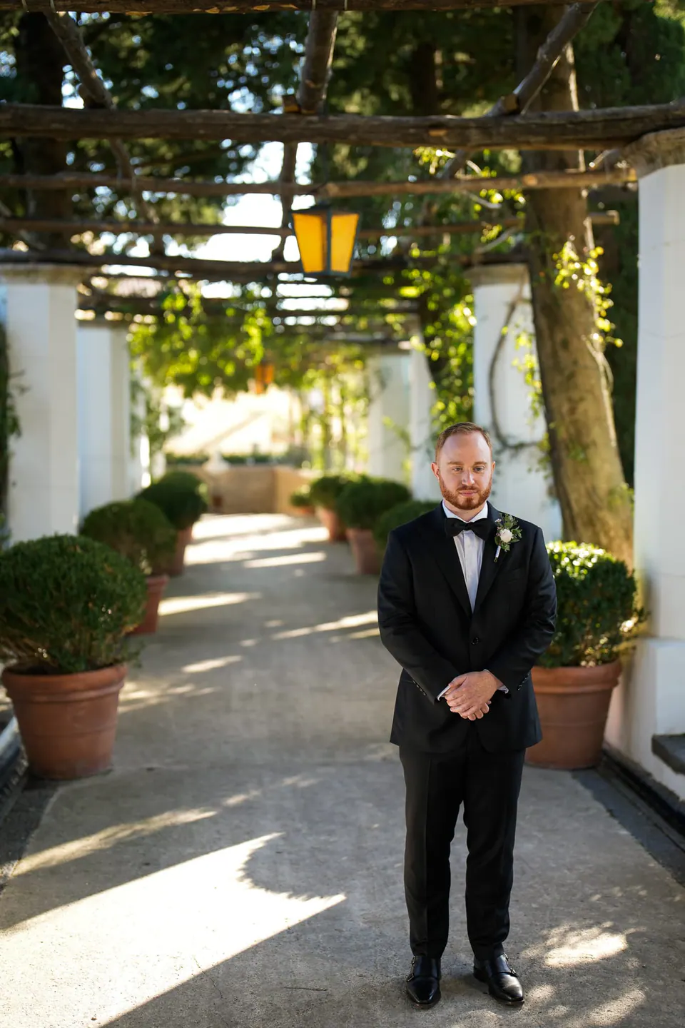 Groom standing alone under the pergola