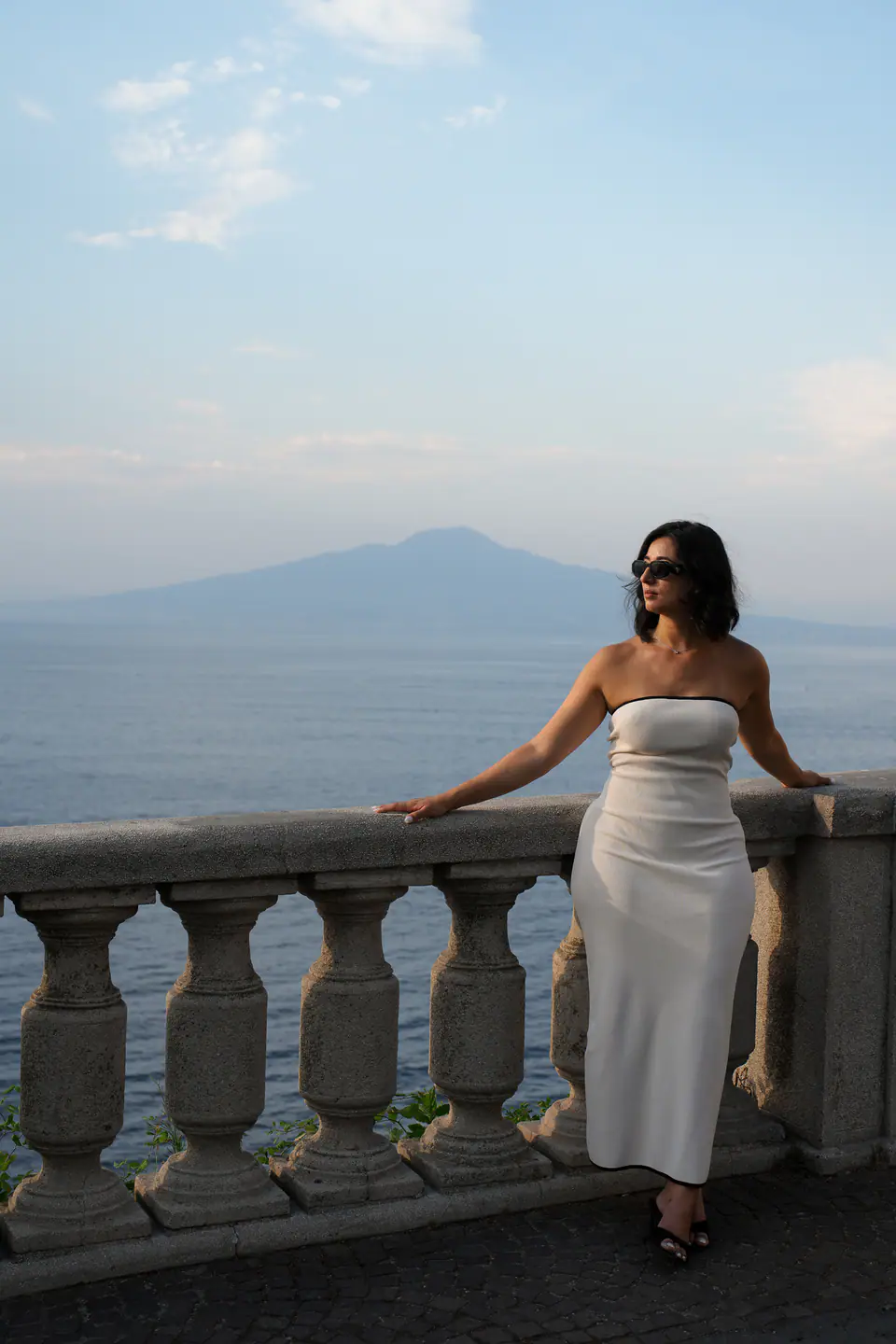 Leaning on a stone balustrade above the Bay of Naples.