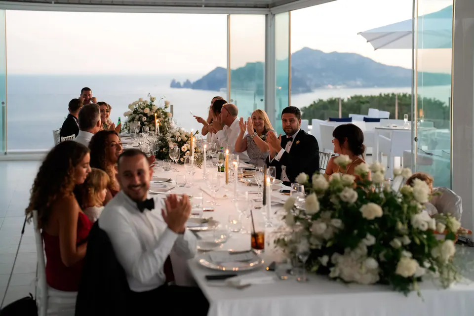 Guests dining on the panoramic terrace, laughter and toasts celebrating love under the Mediterranean sky.
