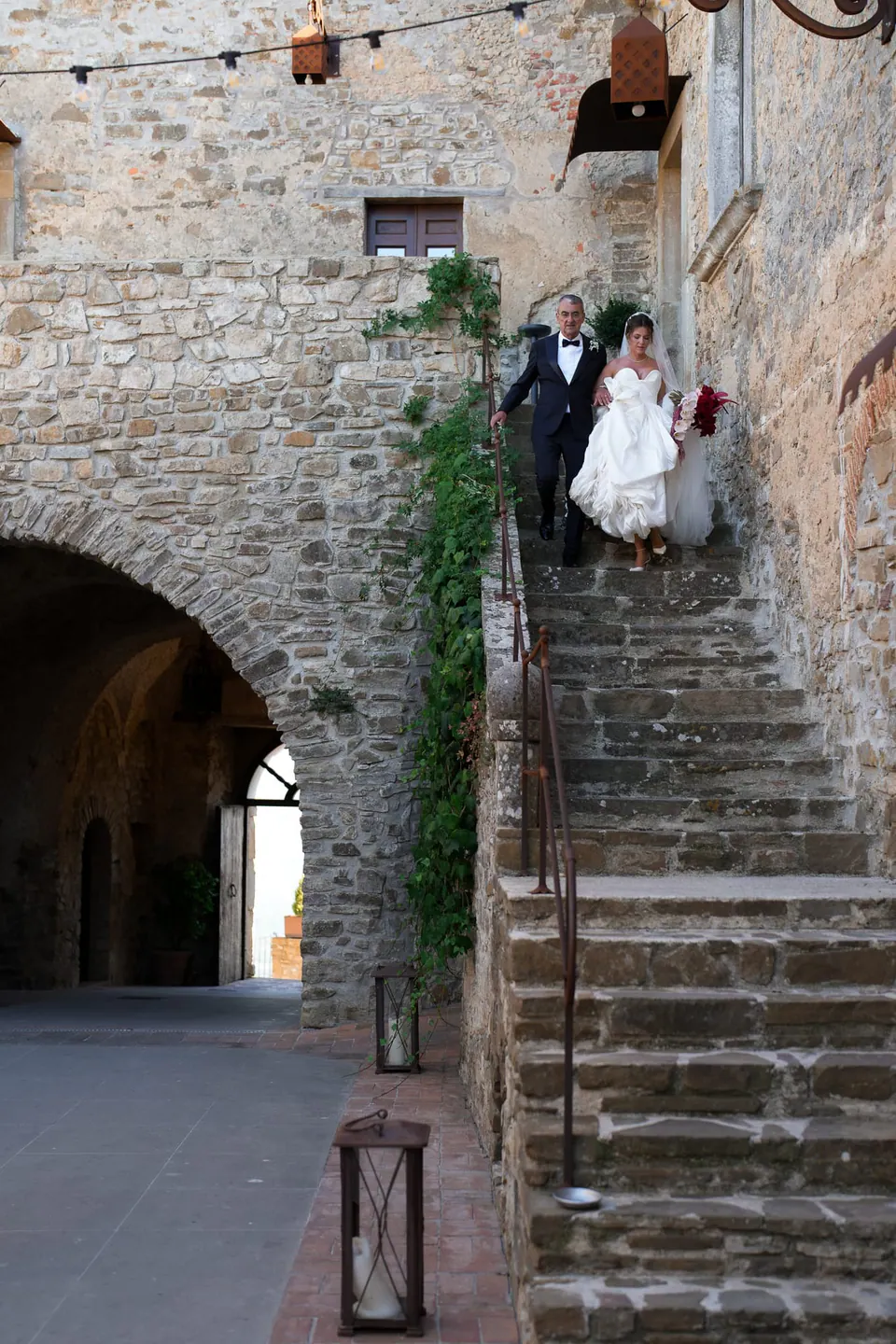 Sposi che scendono la scalinata in pietra del cortile del castello.