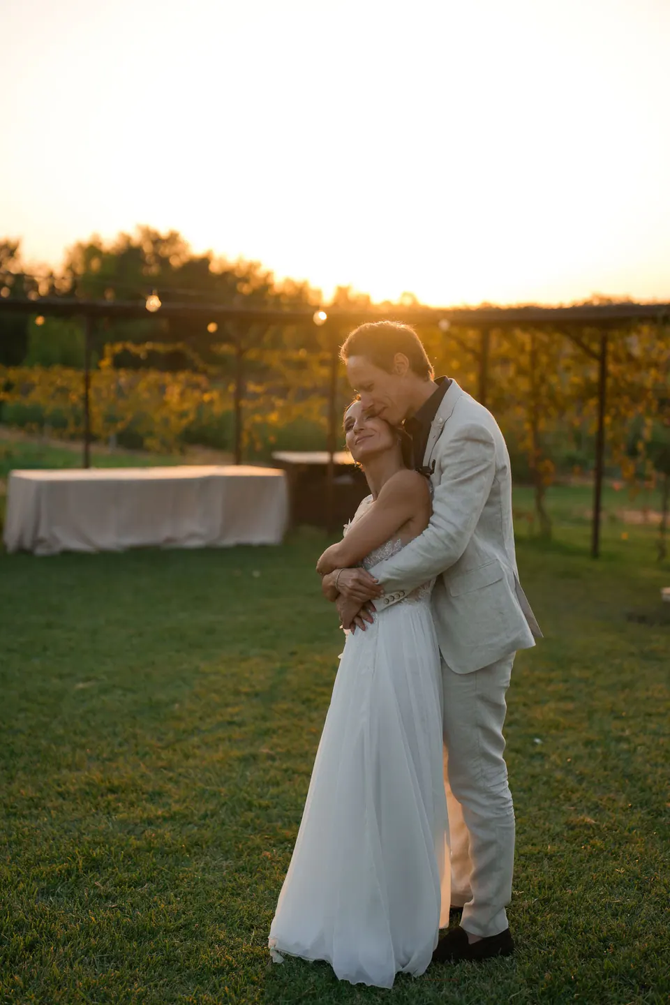 Bride and groom embracing on the lawn at sunset