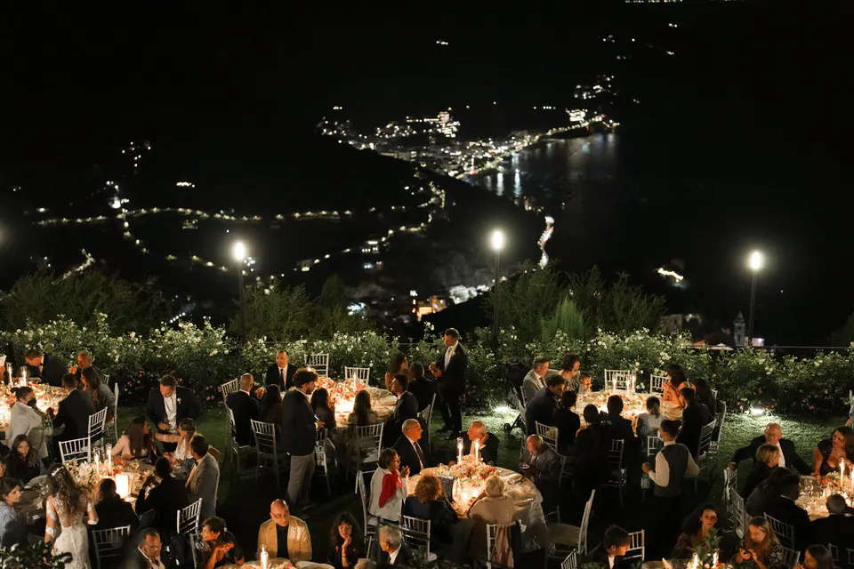Hochzeitsdinner nachts im Garten, unten die Lichter der Küste.
