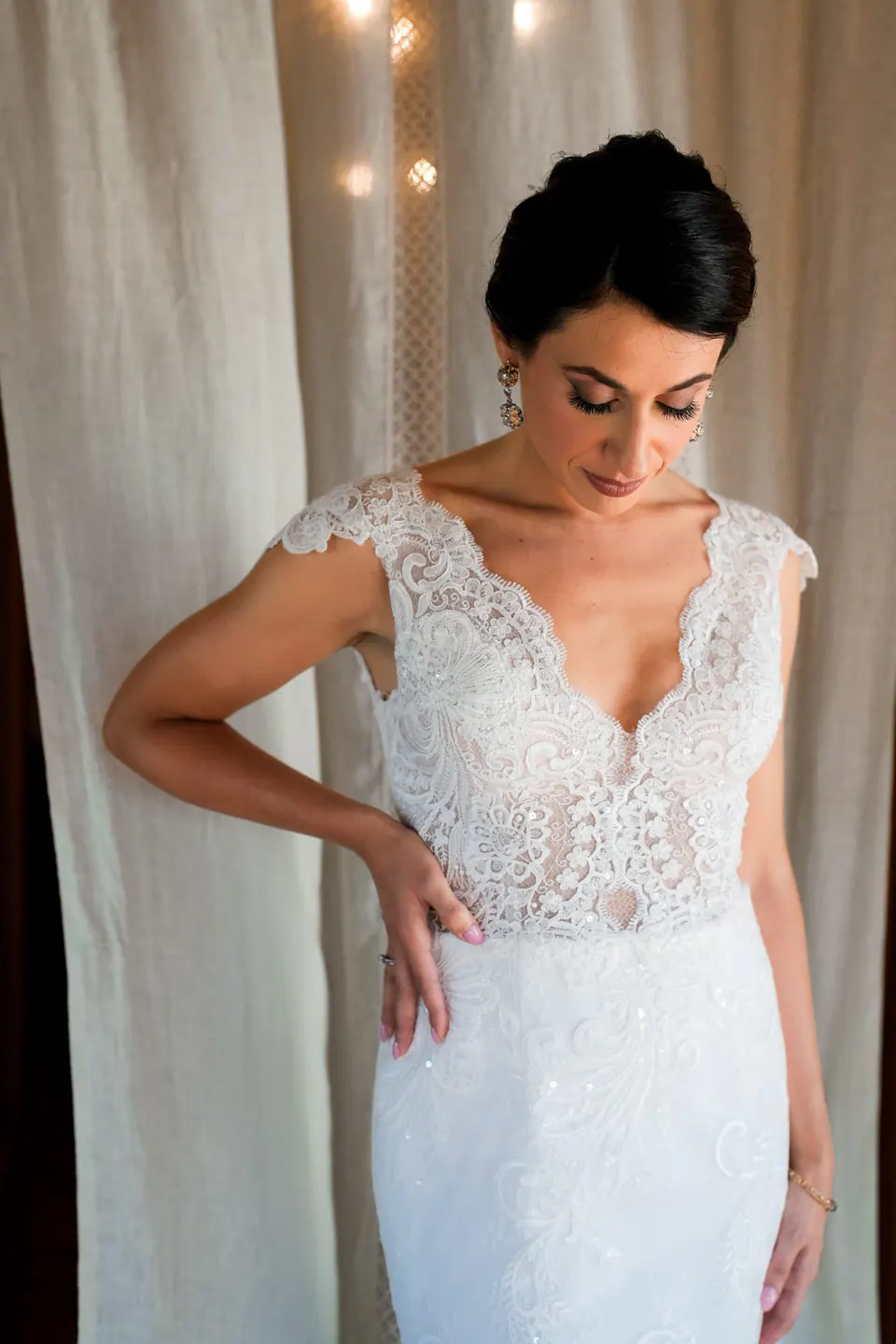 Bride in a lace dress by the curtains