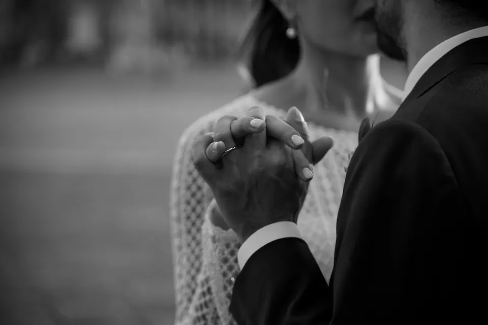 Black and white close-up of the couple's hands clasped together.
