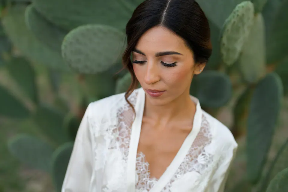 Bride in a lace robe looking down, before getting dressed.