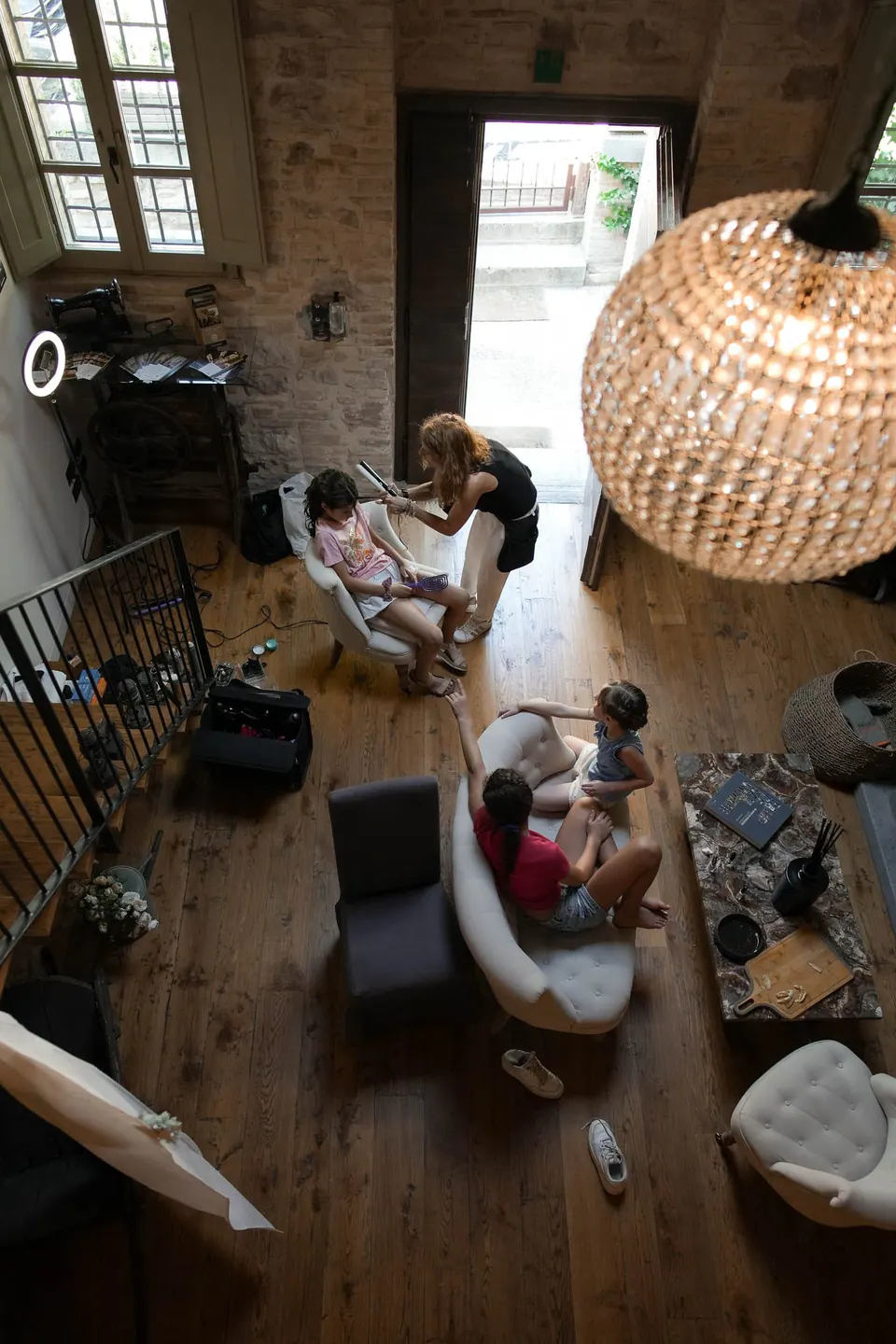 A room seen from above with a rattan lamp, the bride getting ready among friends