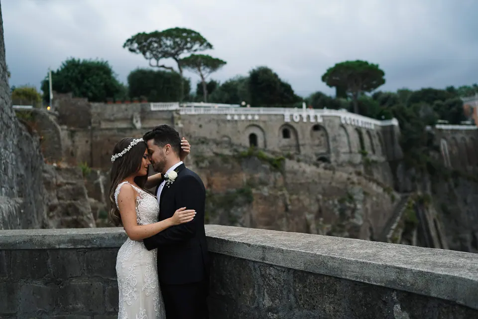 Bride and groom embracing with the cliffs of Sorrento behind them.