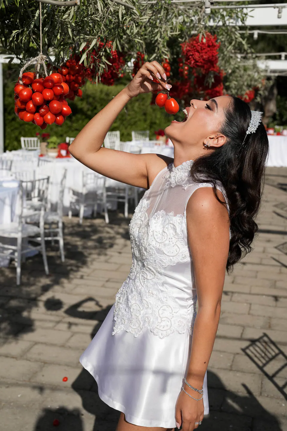 La mariée croque une tomate cerise directement sur la grappe au-dessus des tables.