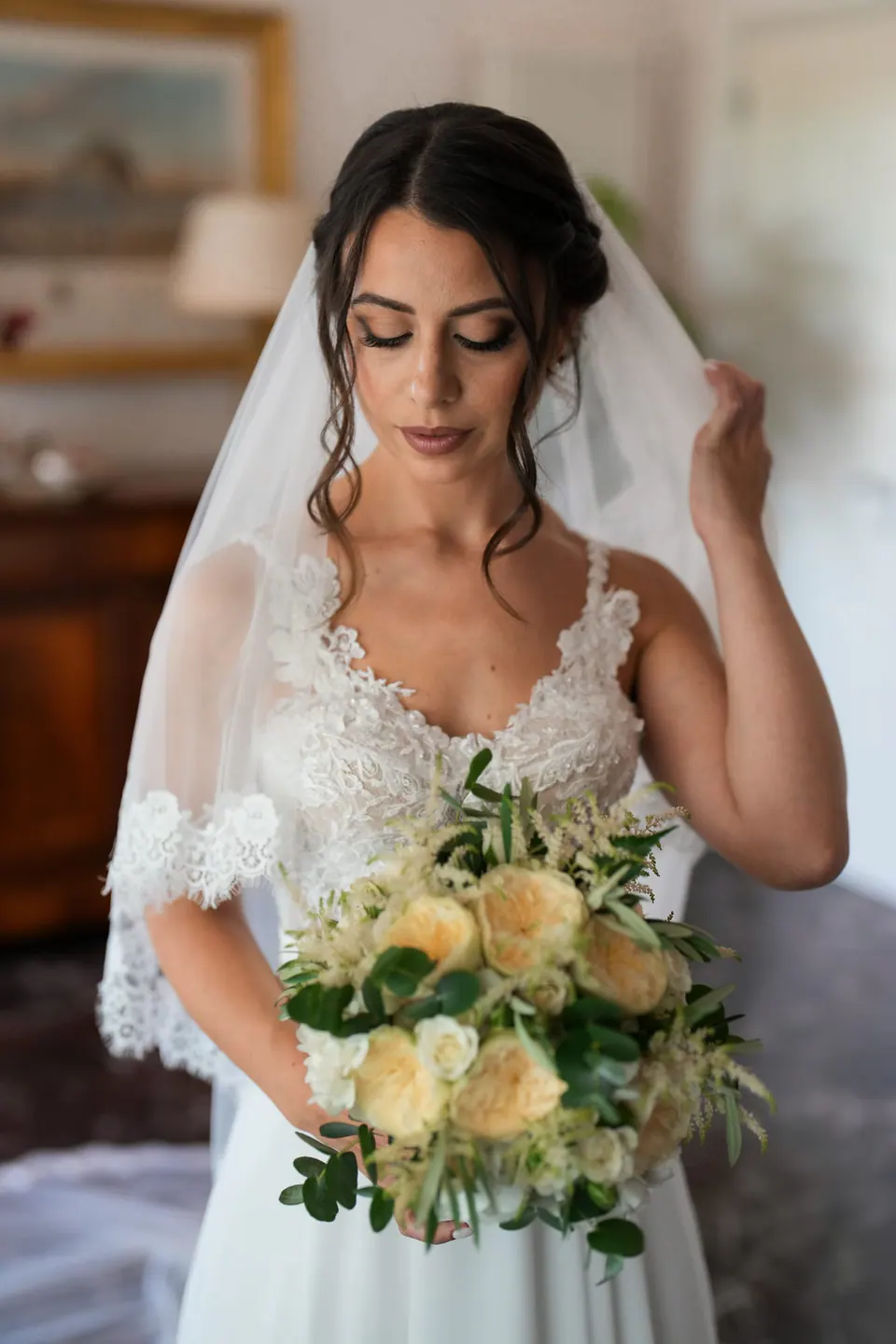 Bride touching her veil gently while smiling, radiant and serene before the ceremony.