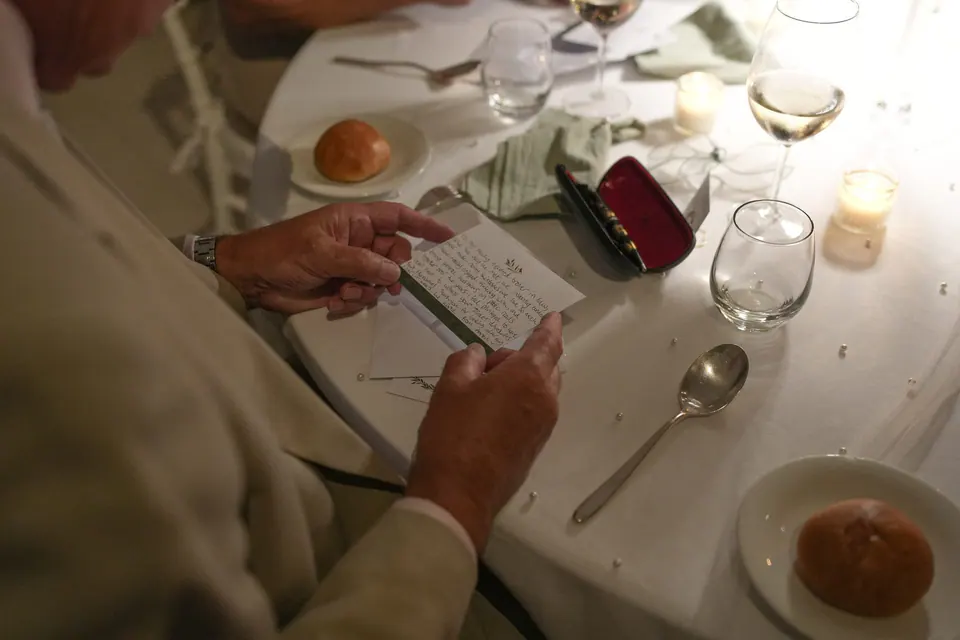 A guest writing on a card at the dinner table