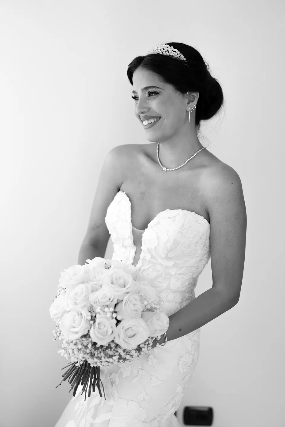 La mariée en noir et blanc, robe bustier en dentelle et bouquet de roses blanches.