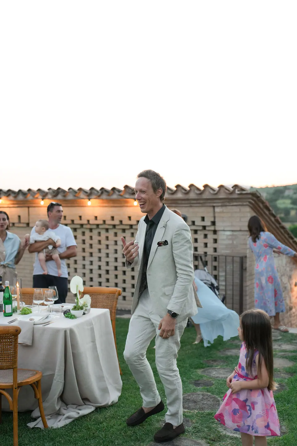 Guests talking and laughing near the dinner tables outdoors.