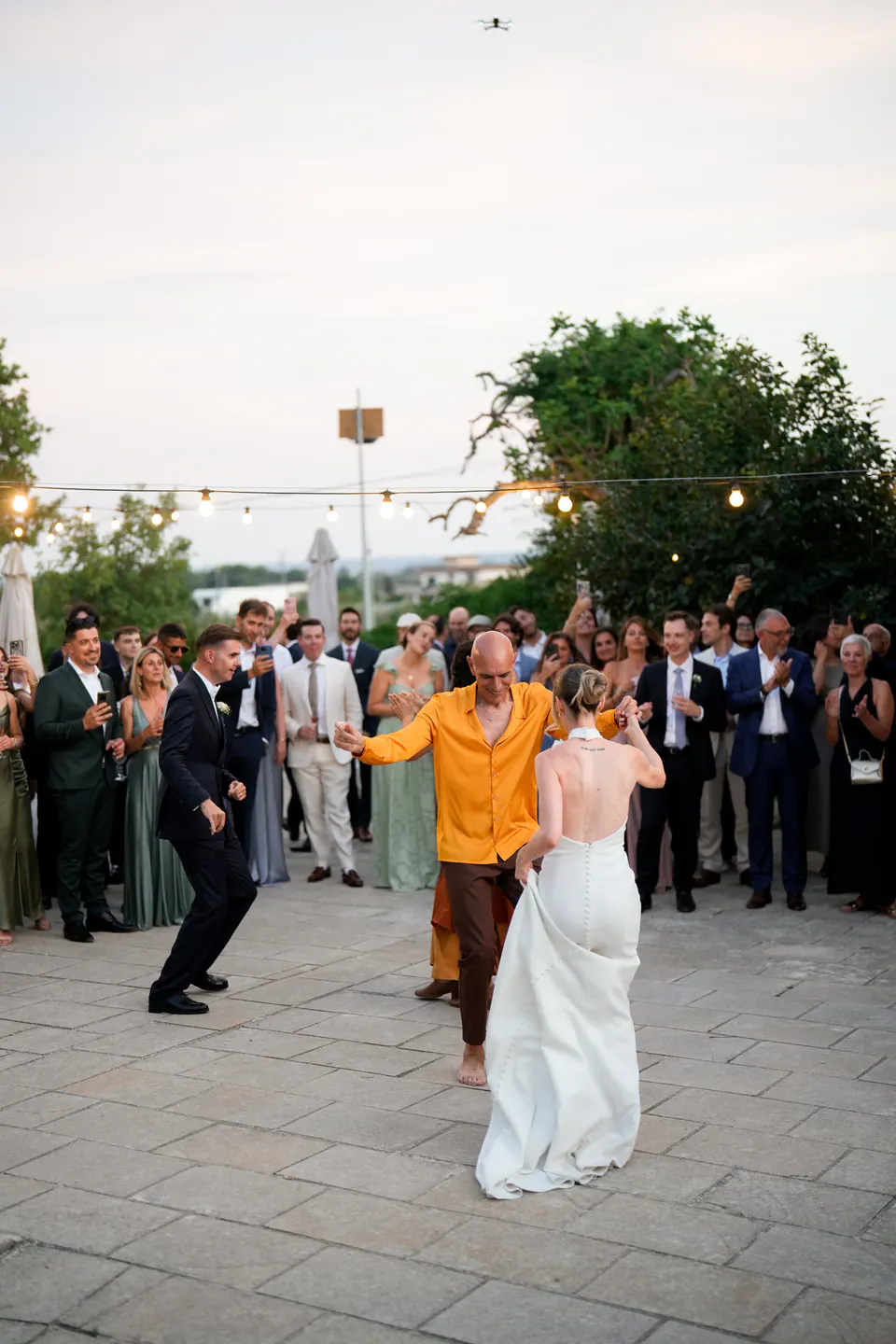 Gli sposi che ballano la pizzica con i ballerini nel cortile, circondati dagli invitati.