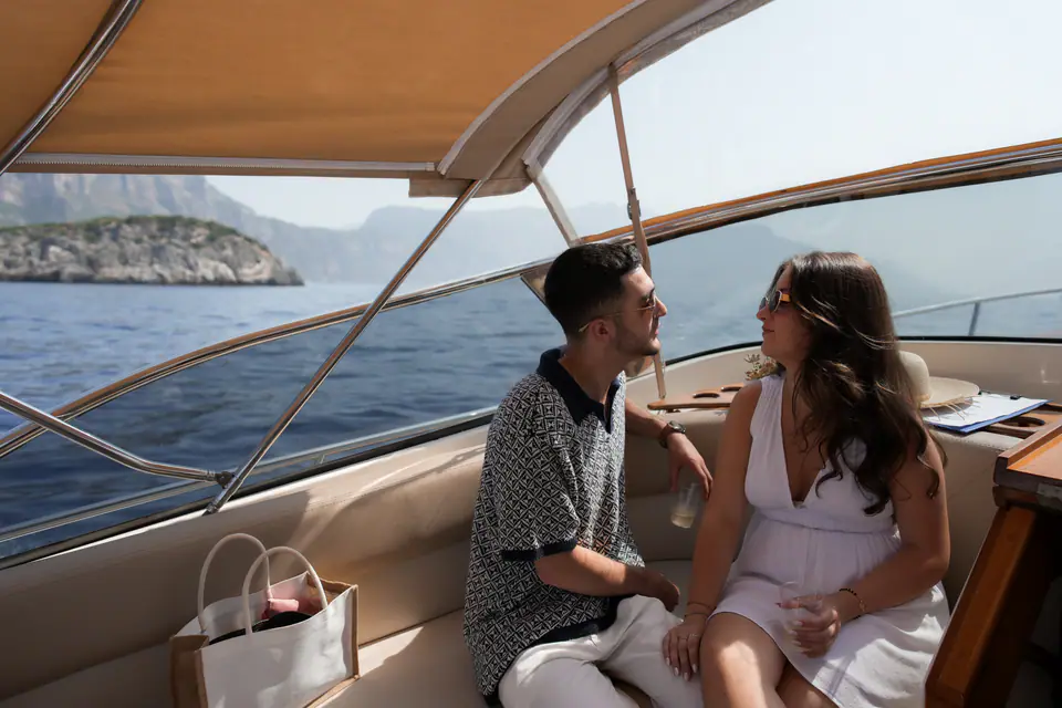 Couple chatting under the boat's awning on the way along the coast.