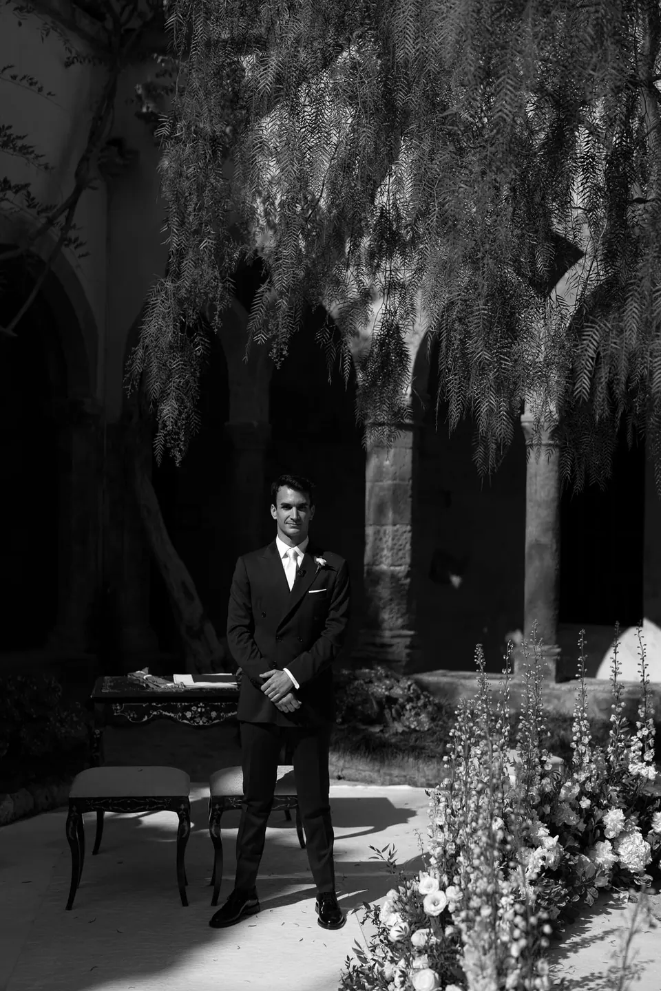 Black and white photo of the groom waiting in a garden of palms