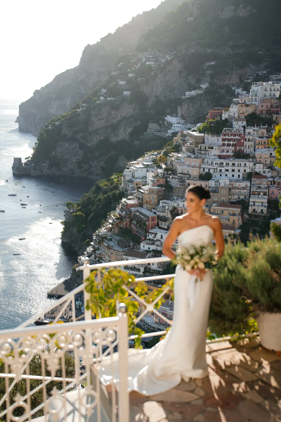 Bride on the terrace with her bouquet, the town falling to the sea.