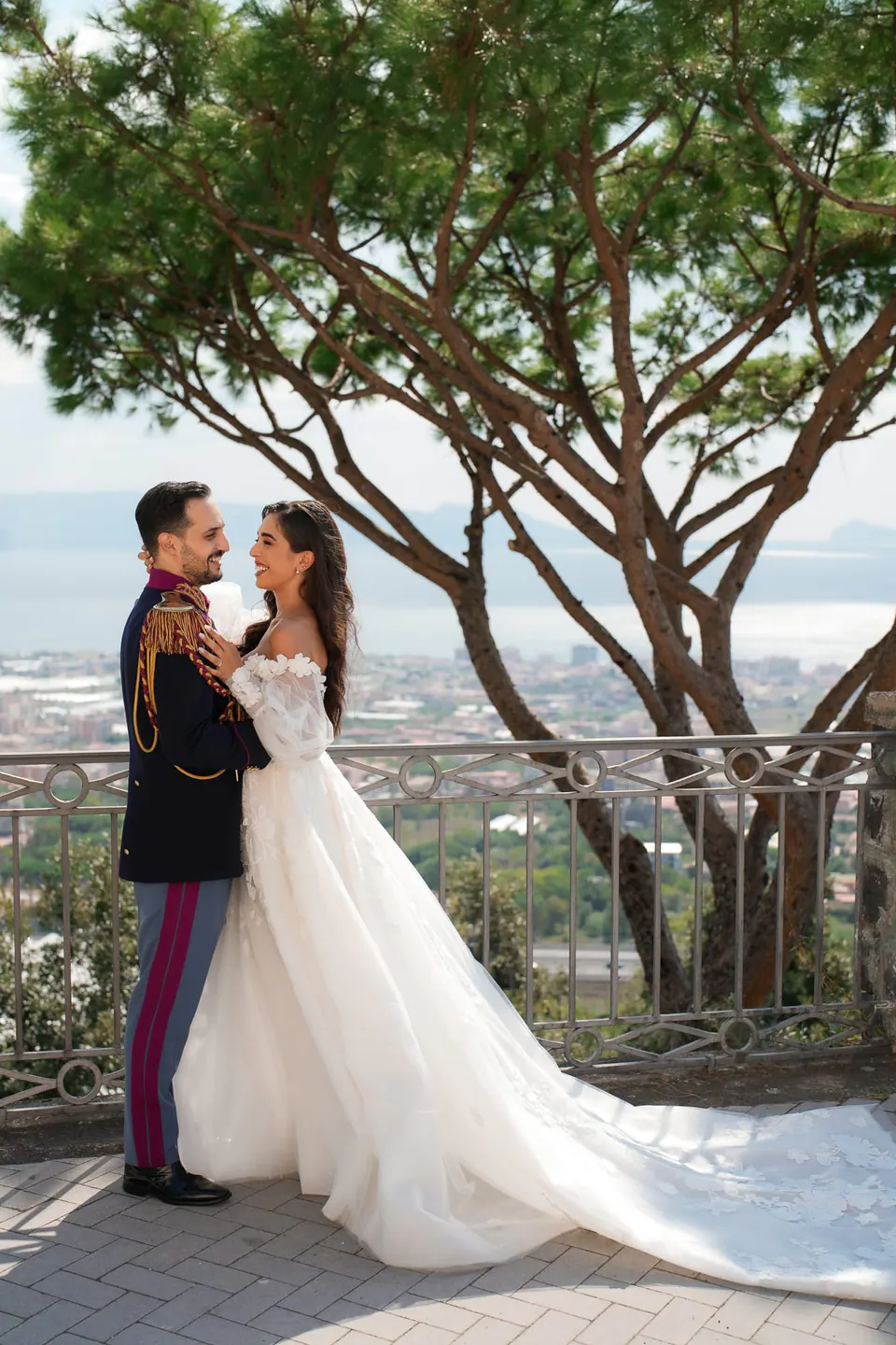 Bride and groom beneath an umbrella pine on the terrace, the gulf below them.