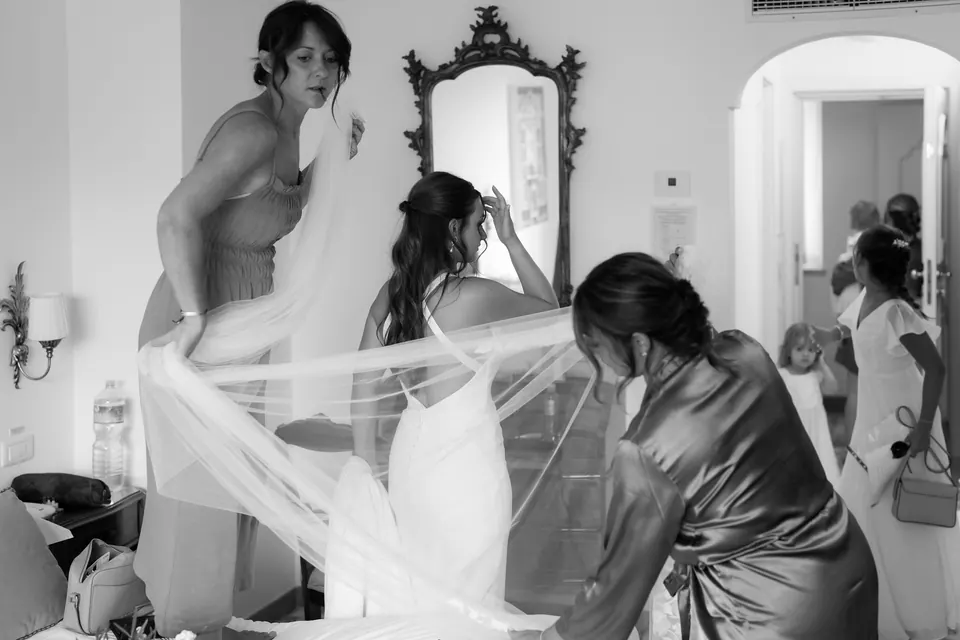 Bridesmaids adjusting the bride’s veil, laughter and affection before the ceremony.