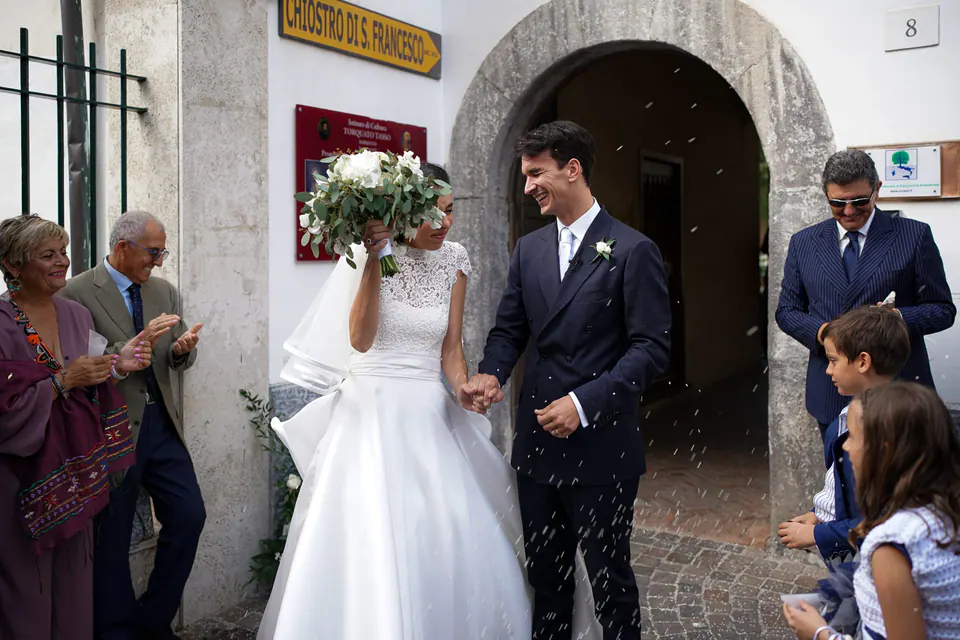 Bride and groom leaving the Chiostro di San Francesco in Sorrento as guests cheer.