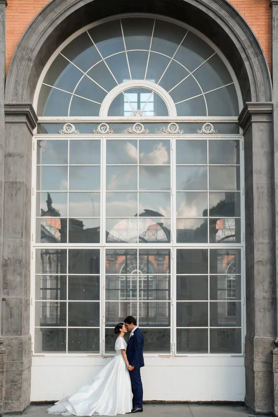 Sposi piccoli sotto un'alta finestra ad arco del palazzo.