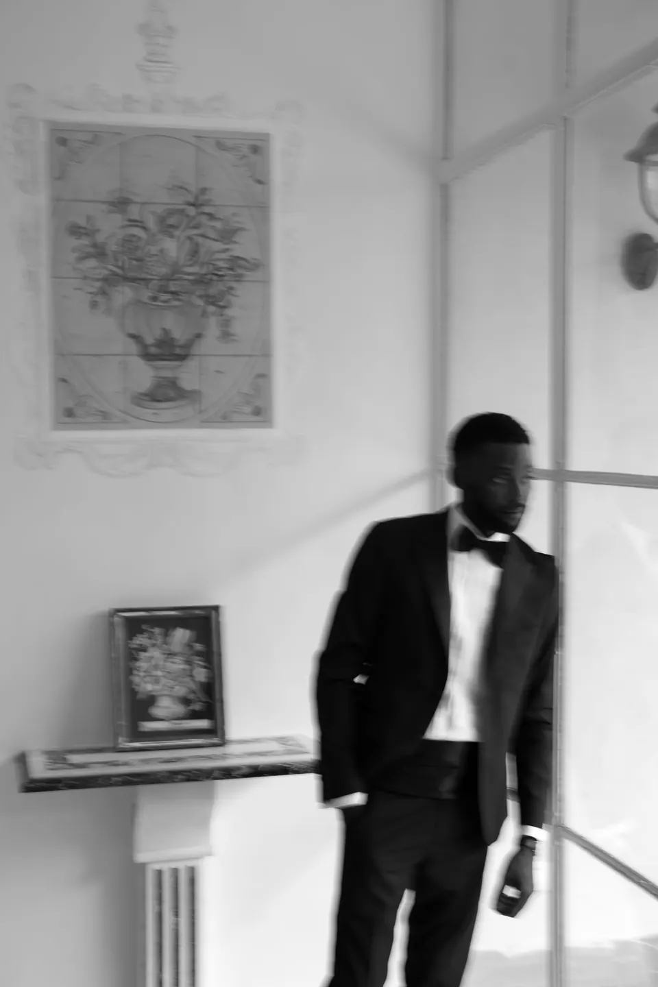 Retrato en blanco y negro del novio con esmoquin en una sala de la villa histórica.