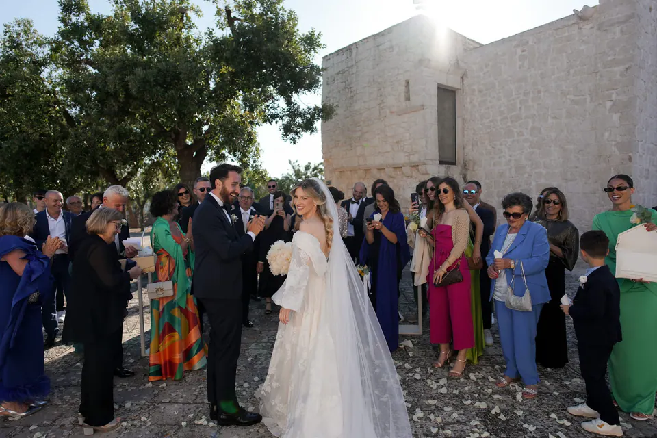Los novios rodeados de familia y amigos en el banquete al aire libre.