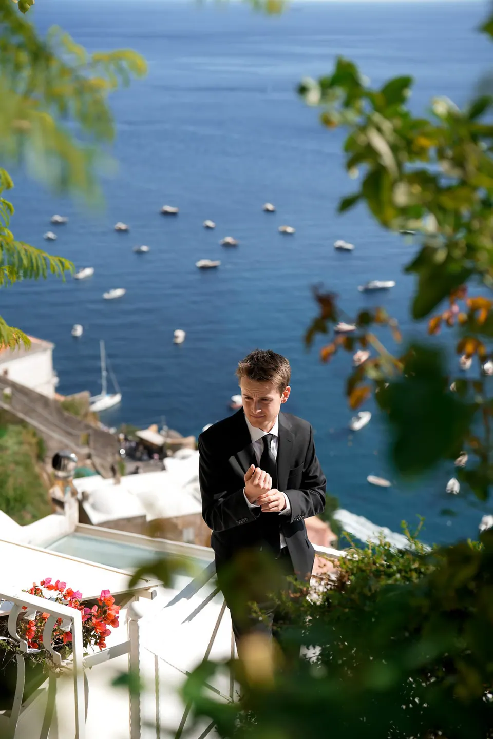 Groom on the terrace above the bay of Positano, boats moored below.
