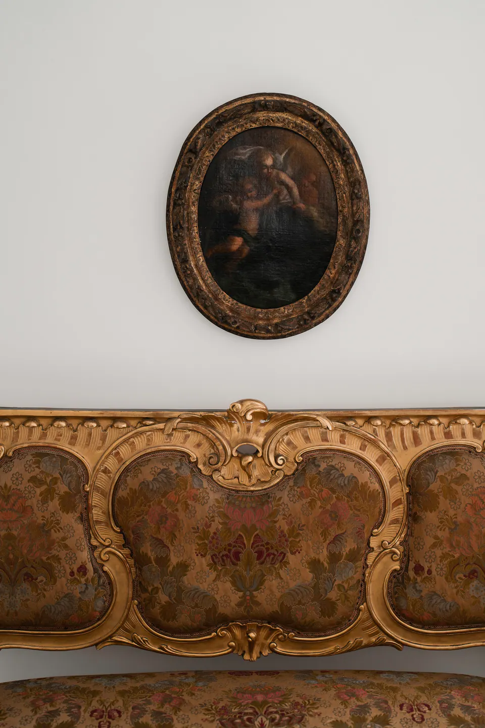 Oval antique portrait above a gilded carved panel in a Neapolitan palace.