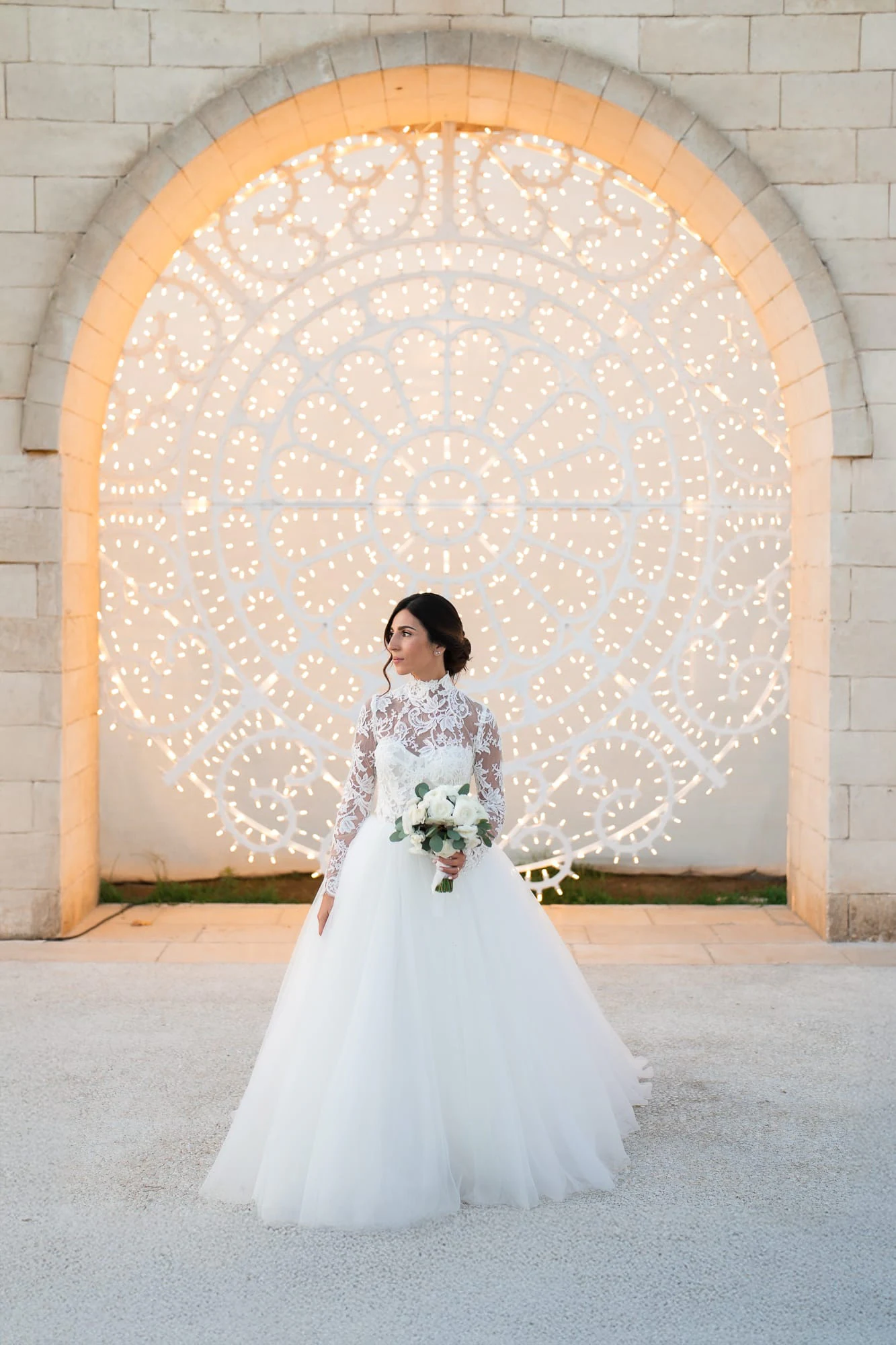 Bride in front of the illuminated carved stone arch of Tenuta San Domenico.
