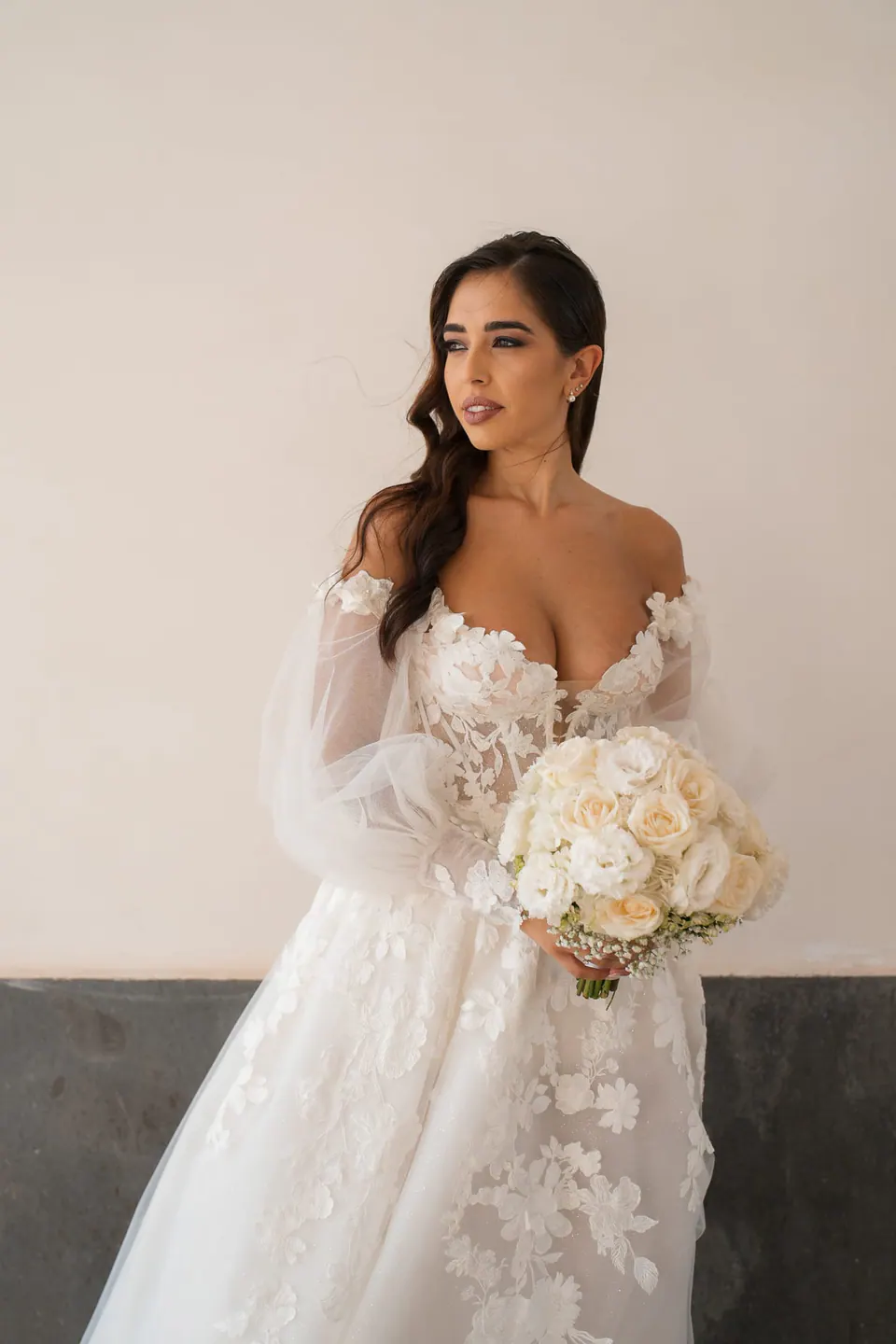Bride holding a bouquet of white roses, portrait in soft indoor light.