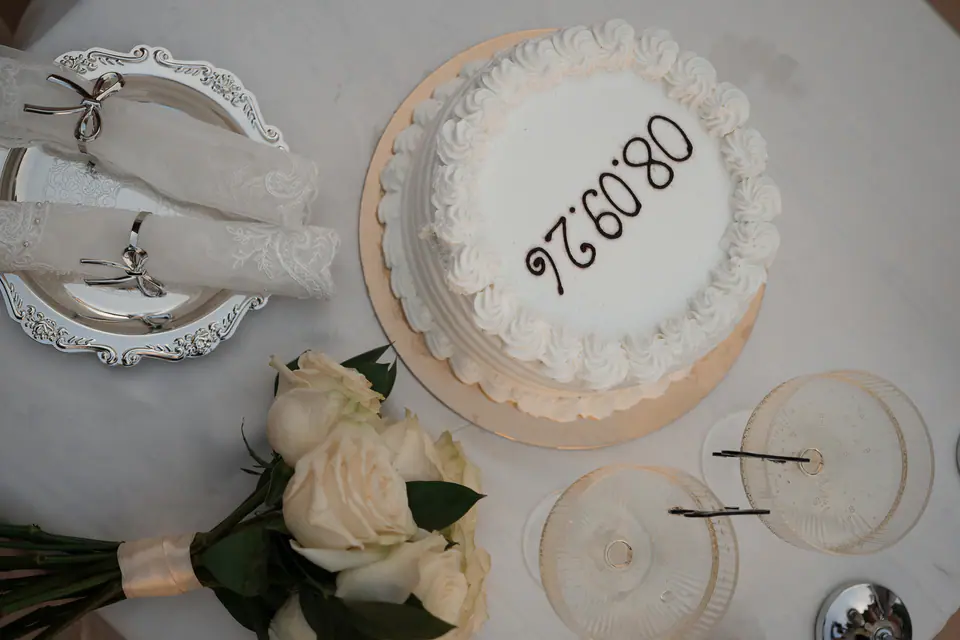Cake with the date of the day, glasses and white roses on the table.