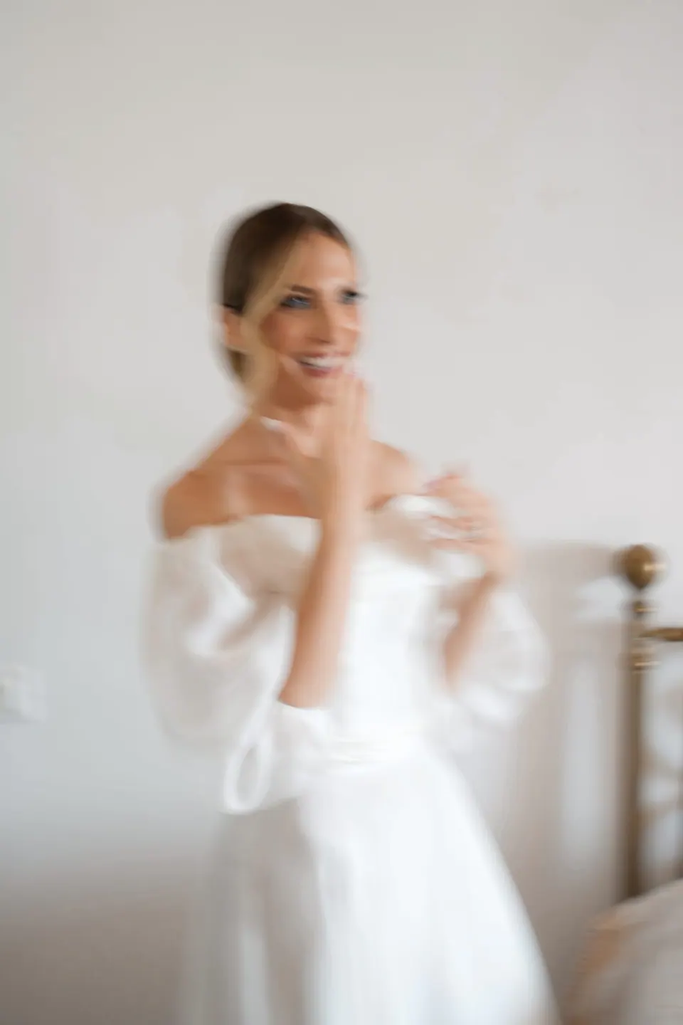 Die Braut lacht im schulterfreien Kleid, weiches Fensterlicht.