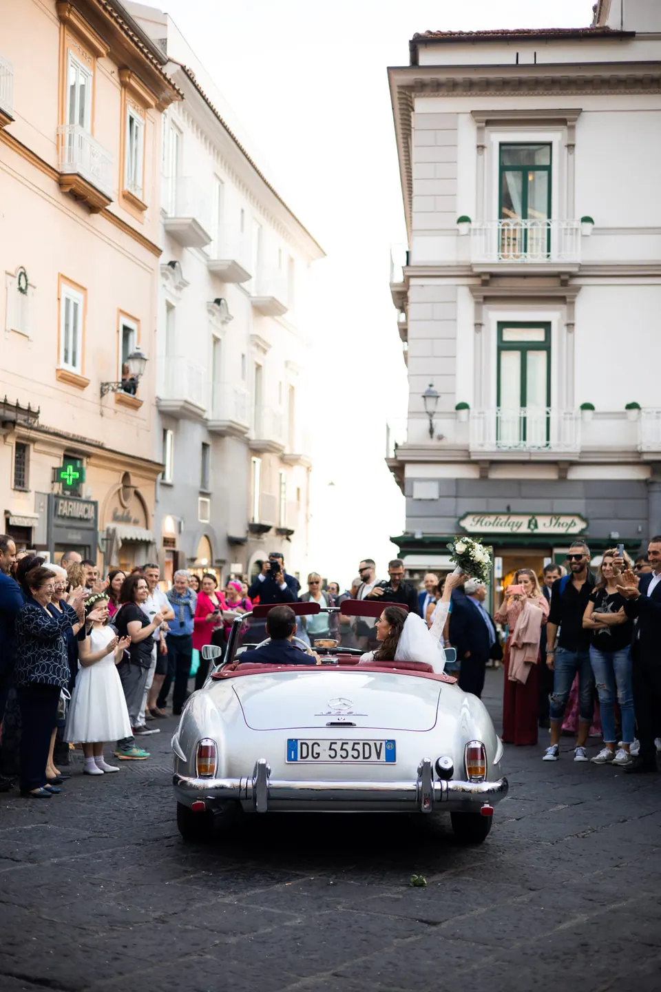 White vintage Mercedes convertible in the streets of Amalfi, a crowd gathered around it.