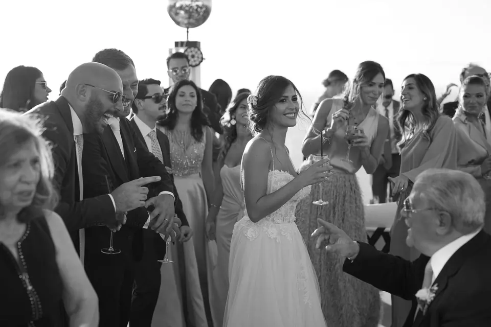Foto in bianco e nero degli invitati che brindano con la sposa all'aperitivo.