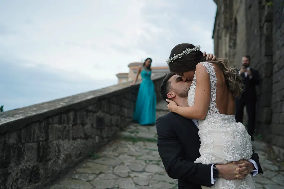 Groom lifting the bride on the stone terrace above the sea.