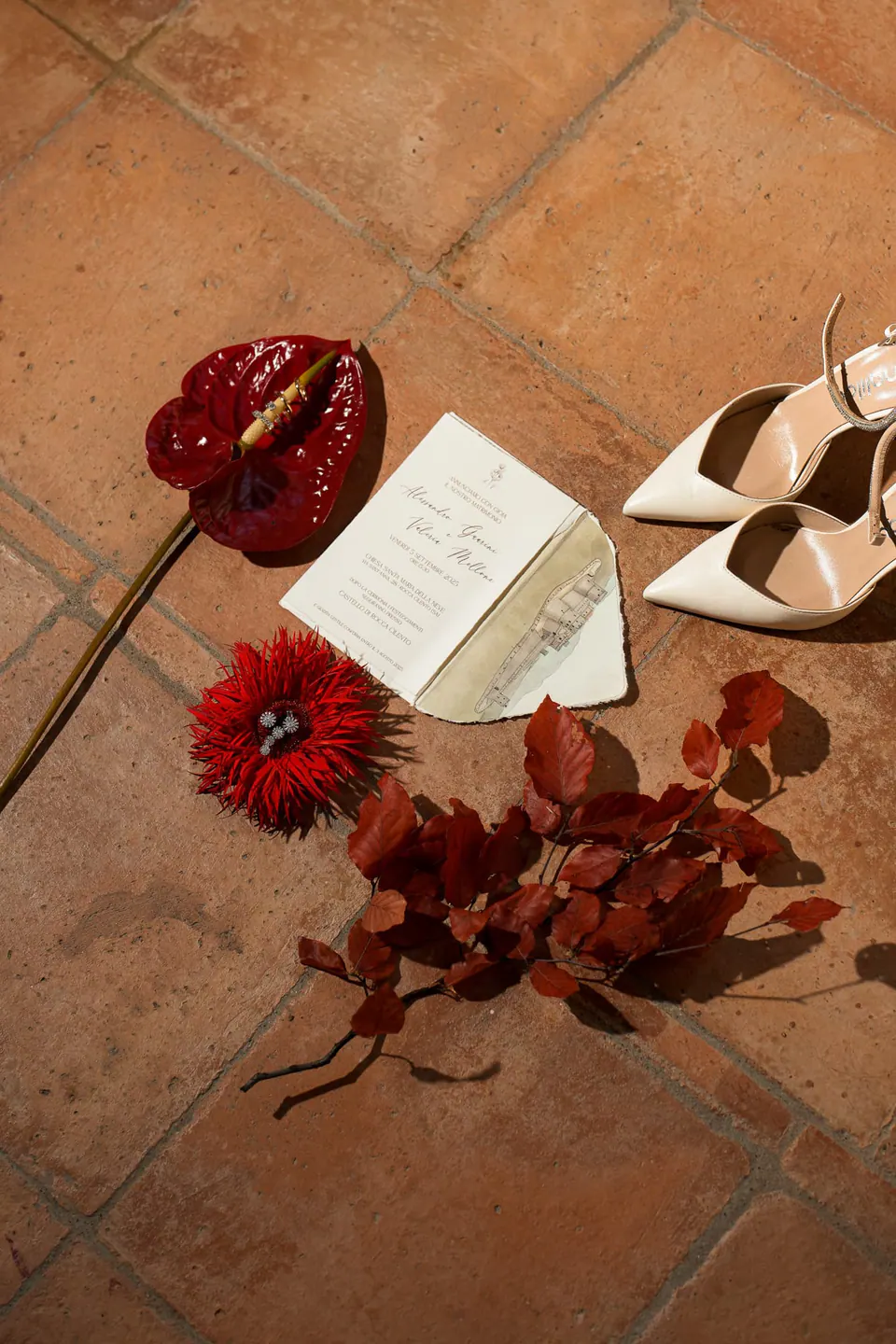 Anthurium rosso, partecipazione e scarpe da sposa sul cotto.