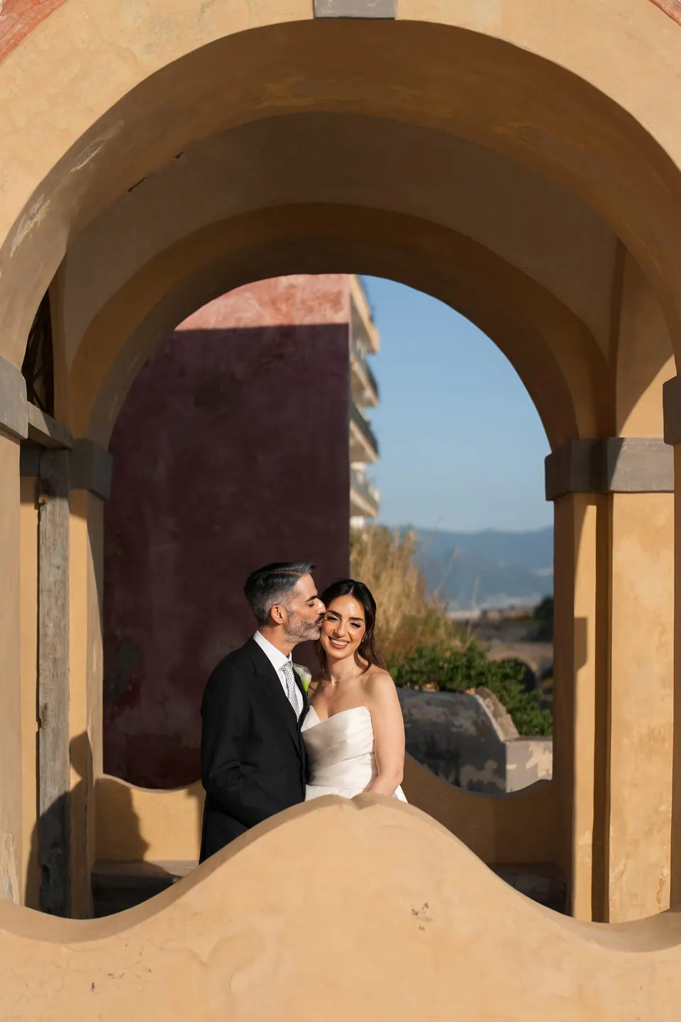 Los novios enmarcados por un arco de piedra curvo.