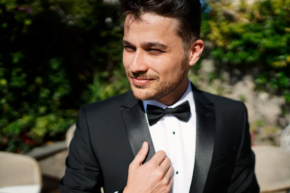 Groom in a tuxedo smiling.