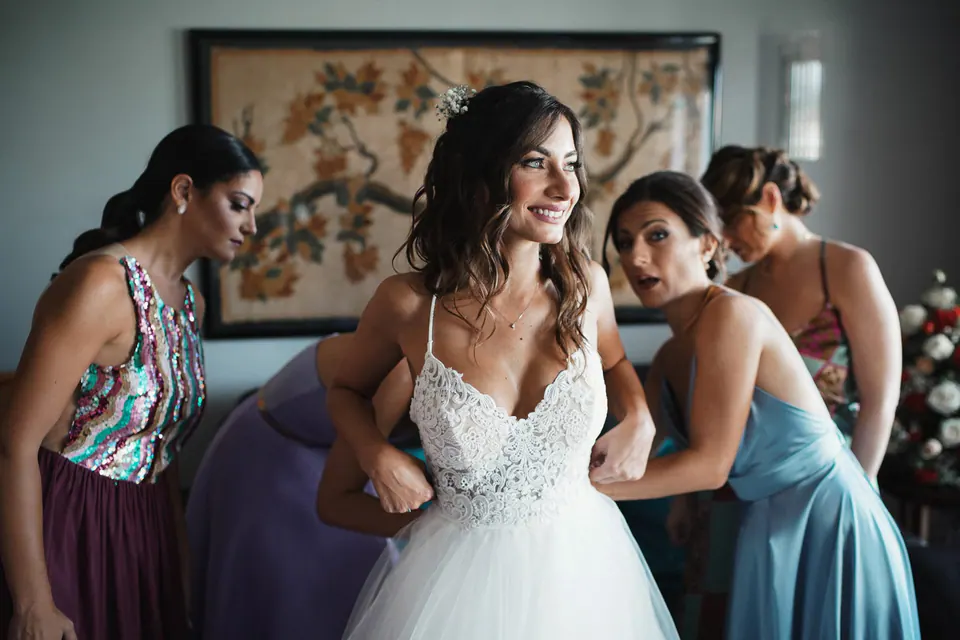 Sposa che ride con le damigelle che la abbracciano prima della cerimonia.