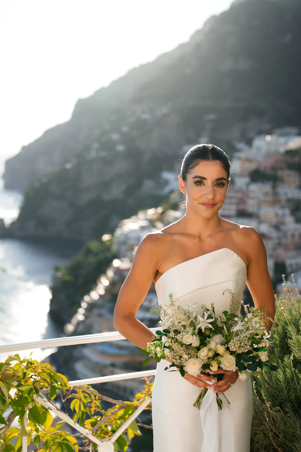 Bride holding her bouquet on the terrace in the evening light.