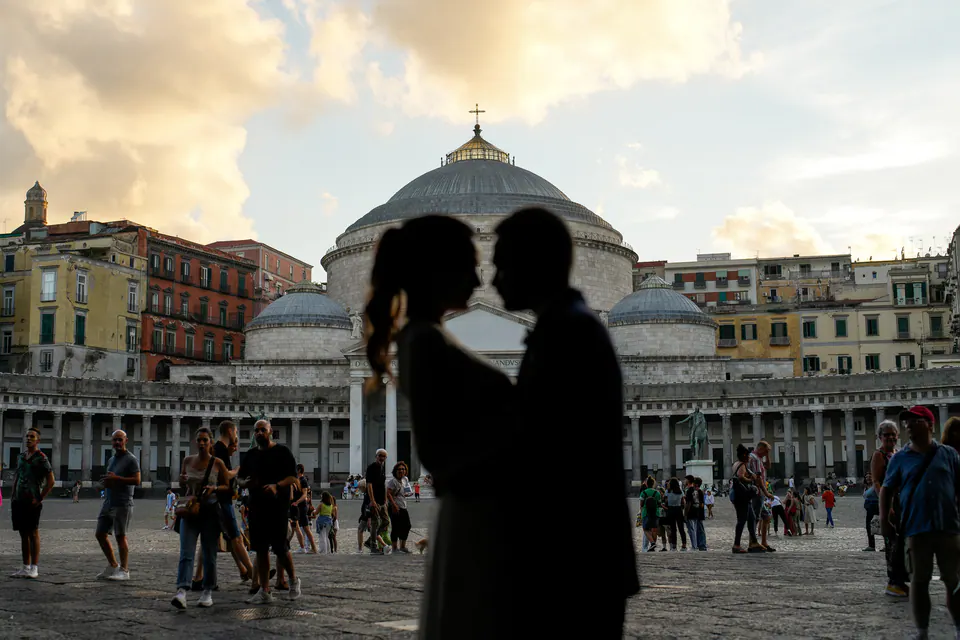 Couple framed by the architecture of Piazza del Plebiscito, romantic kiss at sunset.