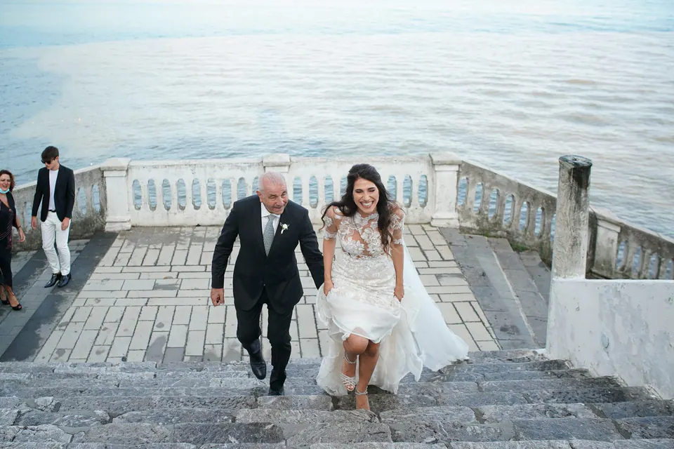 Bride walking with her father across a terrace above the sea at Belmond Hotel Caruso, Ravello.