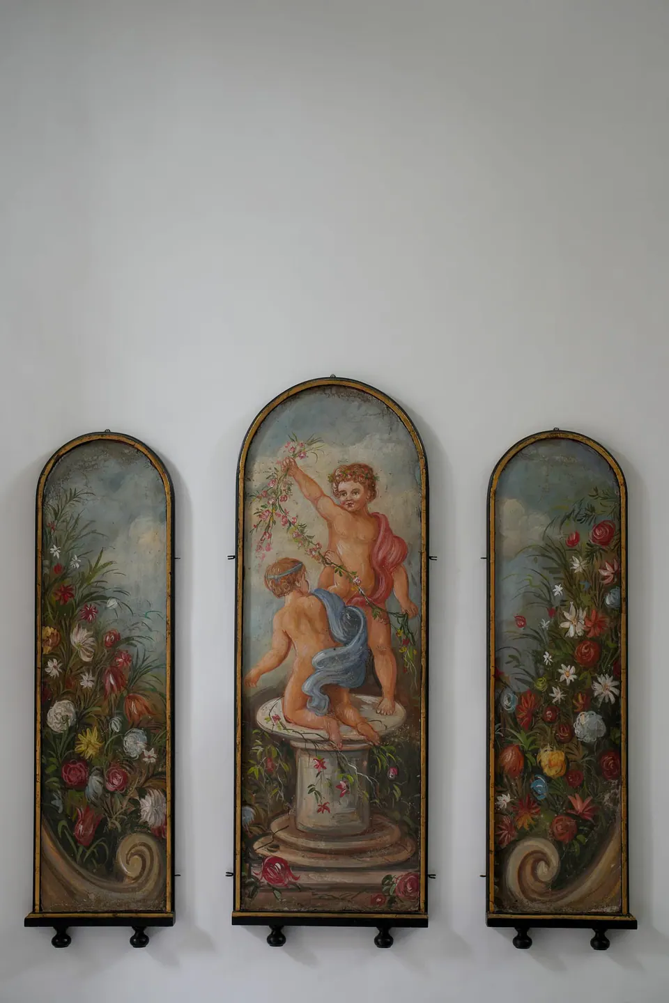 Drei bemalte Keramiktafeln an einer weißen Wand.