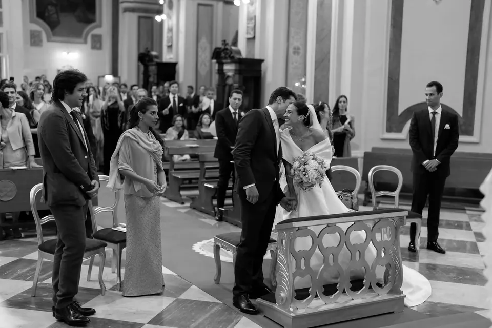 Foto in bianco e nero degli sposi all'altare durante la cerimonia in chiesa.