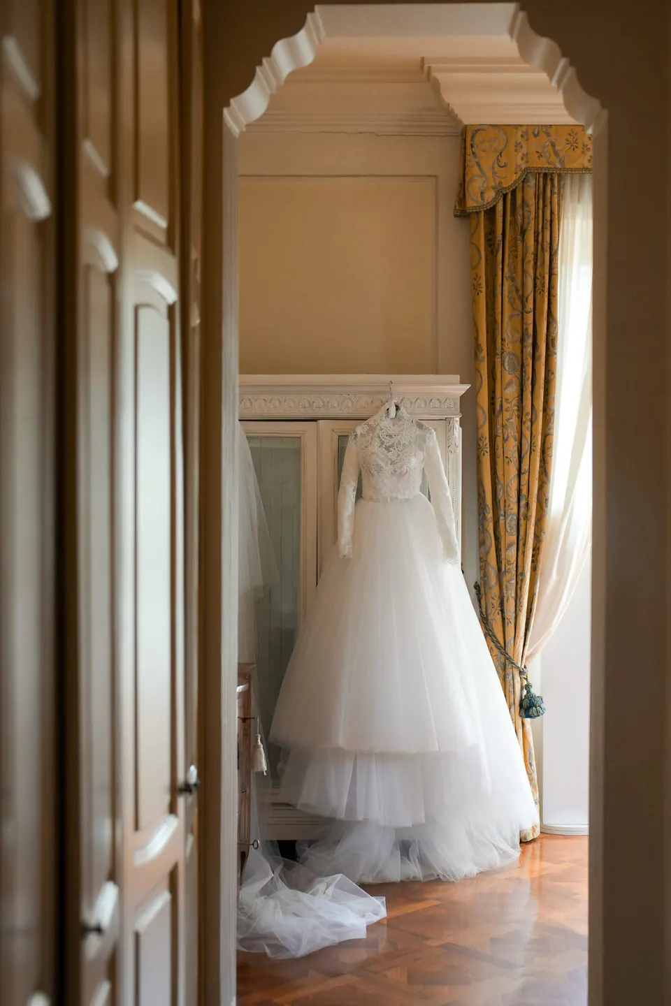 The wedding dress hanging in a room, seen through a doorway
